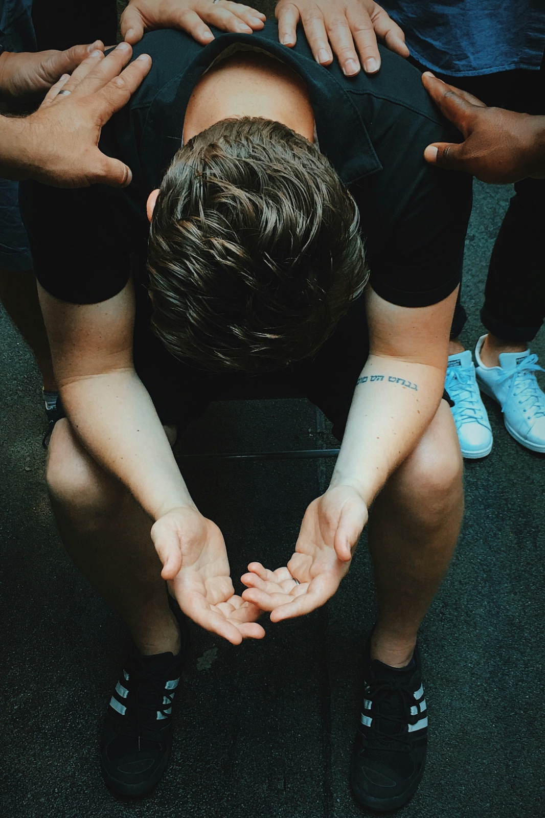 Students praying over a classmate with hands laid on his shoulders