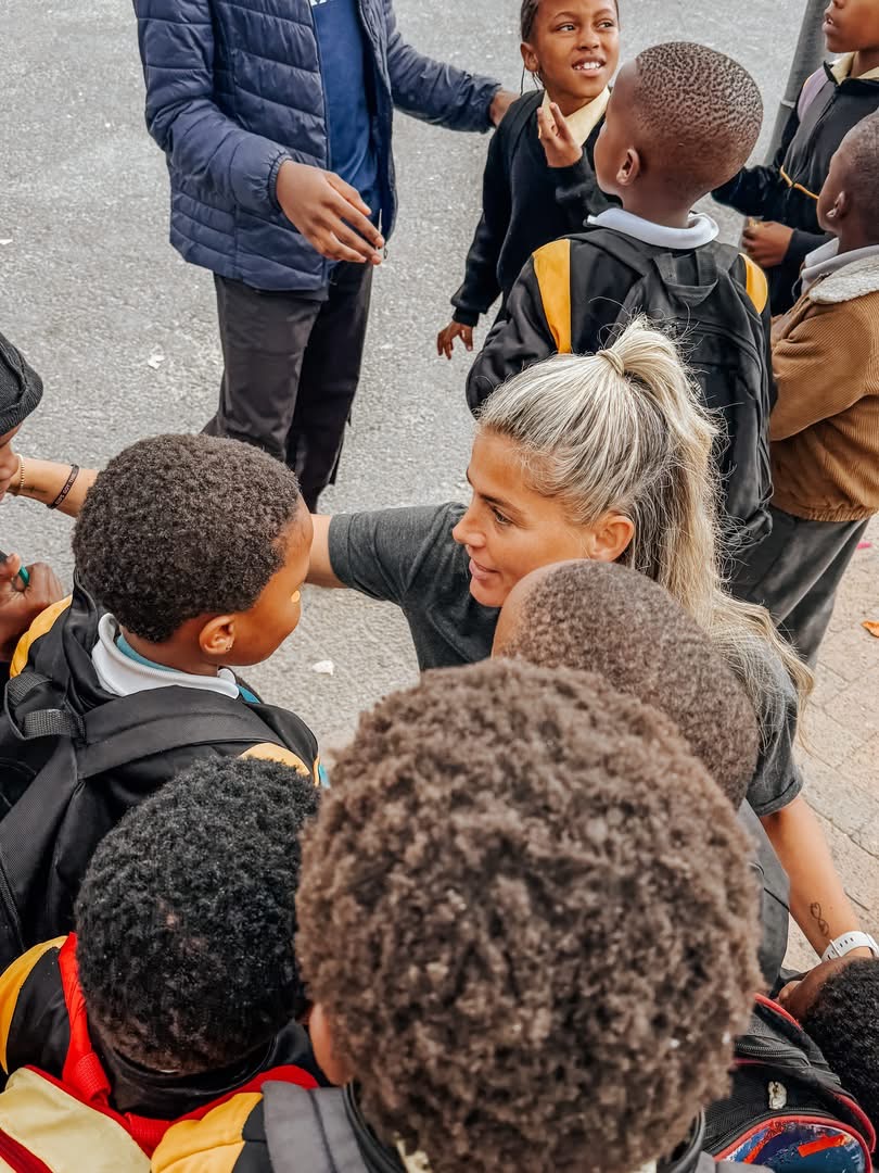 A woman greeting schoolchildren during a community outreach